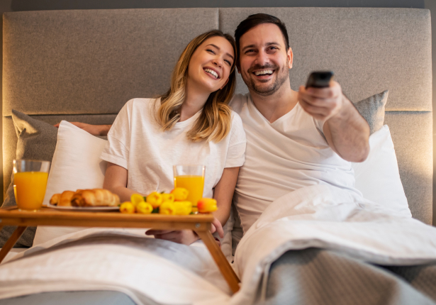 Couple with Hotel Room Service in bed watching in-room entertainment